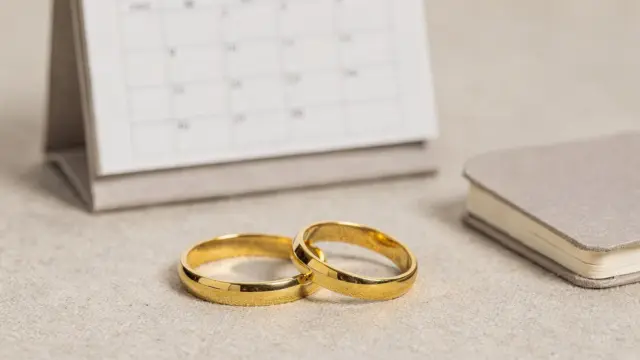 Trauringe auf einer Schmuckablage mit Kalender für die Hochzeitsplanung