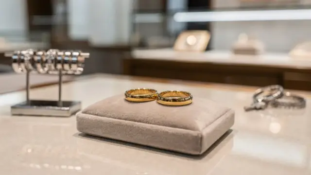 Trauring-Beratung beim Juwelier mit zwei Goldringen, Ringmaß und Schmucktablett