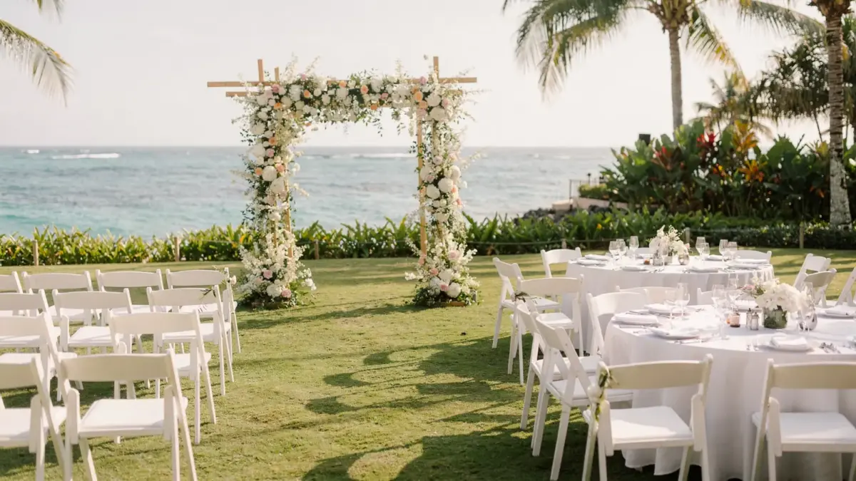 Destination-Wedding-Setup mit Traubogen, Stühlen und Blumendeko am Strand