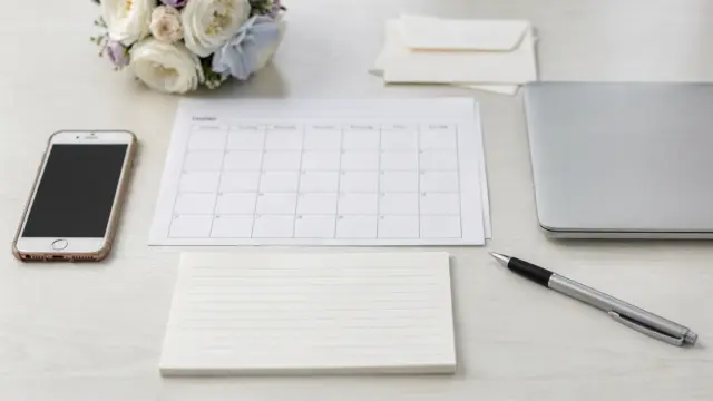 Hochzeitsplanung mit Kalender, Smartphone und Notizblock zur Bestätigung von Dienstleistern